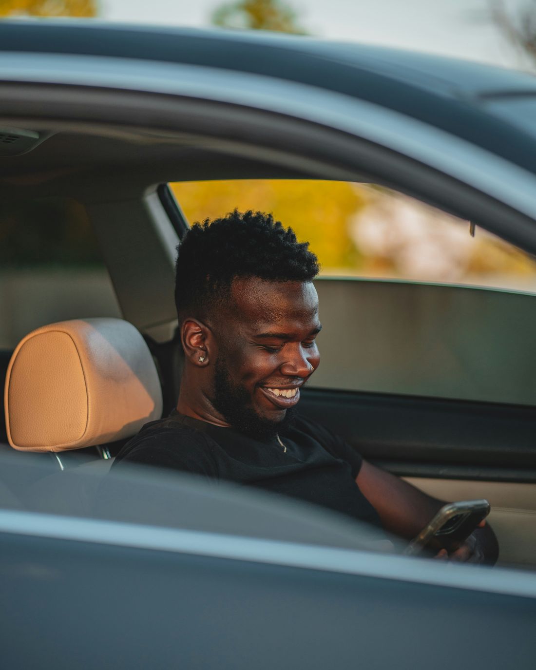 A rideshare driver smiling in his car